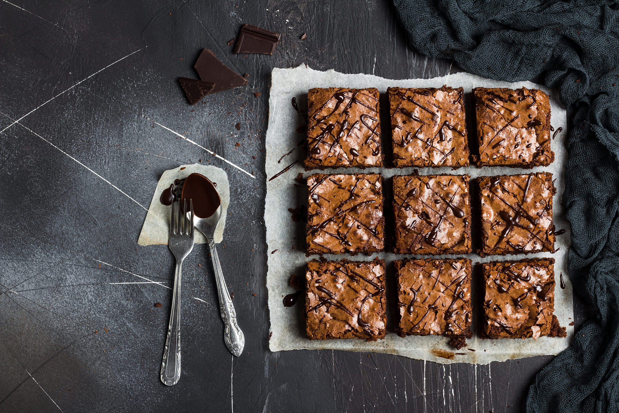Chocolate brownie cake piece pie homemade pastries sweet cooking with spoon of melted chocolate on dark background top view flat lay